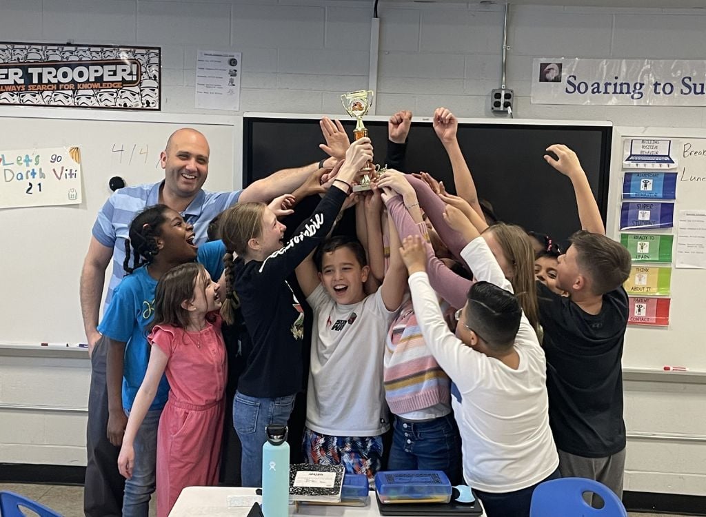 Students and taacher celebrate with a Sumdog trophy