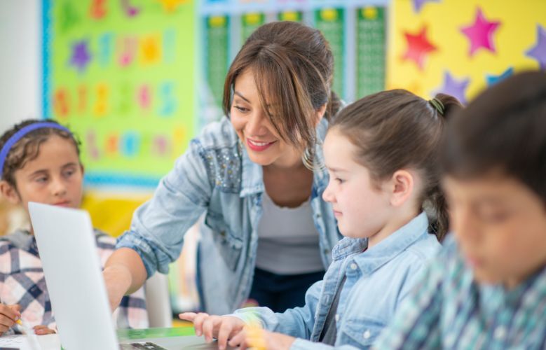 Teacher helping student on laptop